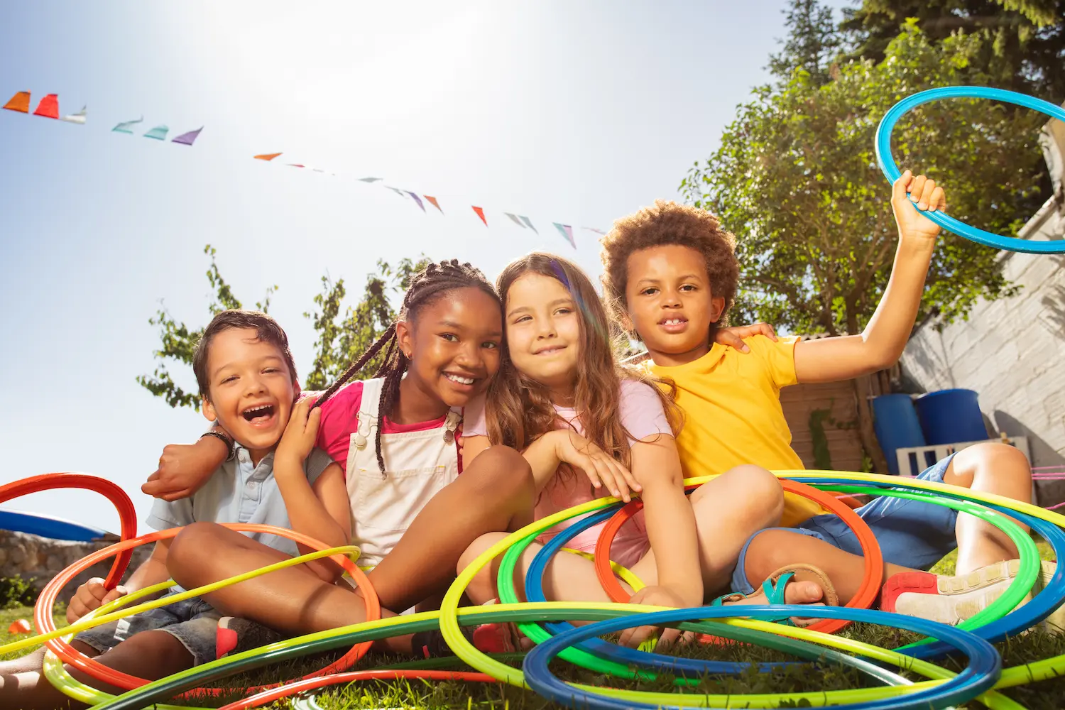 Happy laughing kids sit with hula rings in garden
