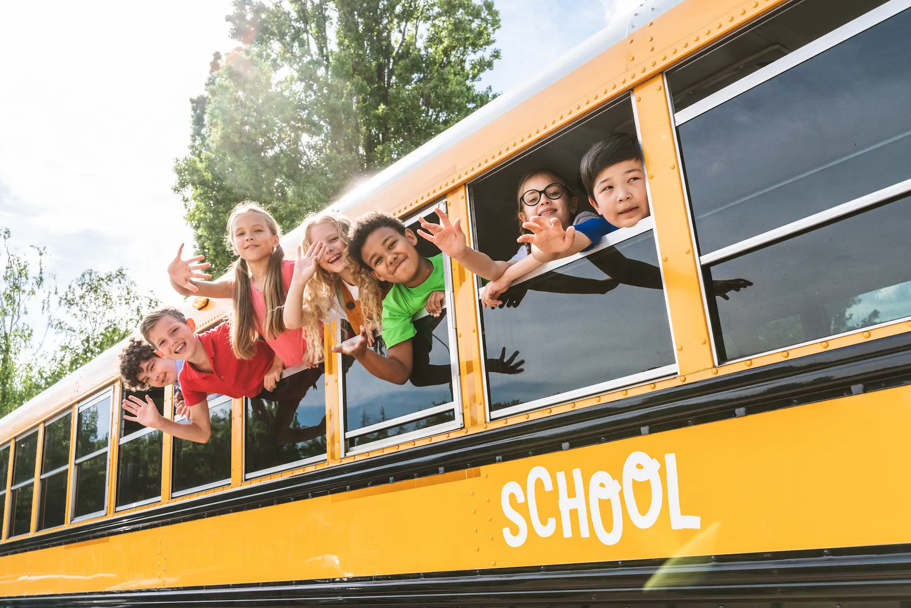 Group of young students attending primary school on a yellow school bus