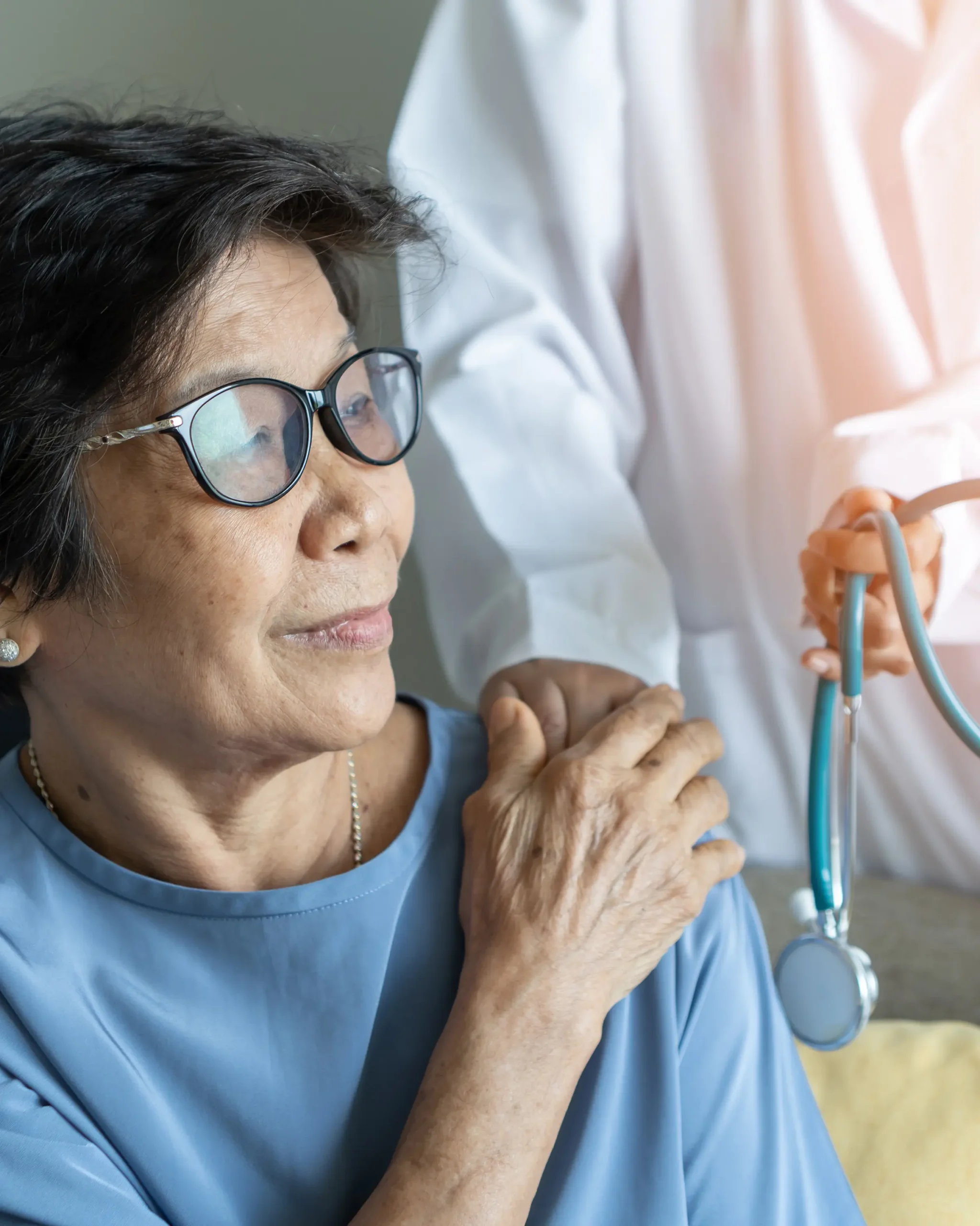 Older asian woman with a doctor's hand on her shoulder