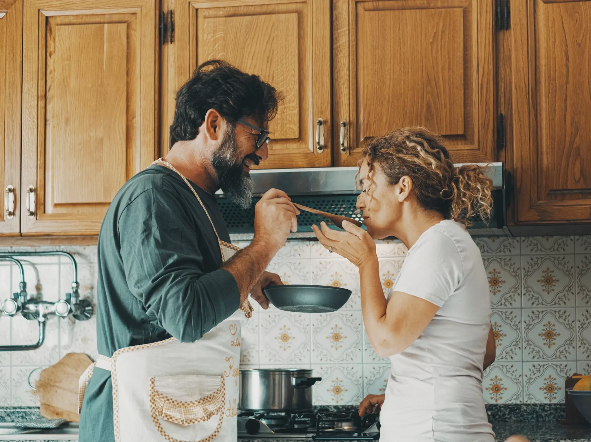 One happy real couple at home enjoying life together and relationship. Man giving food to woman to taste.