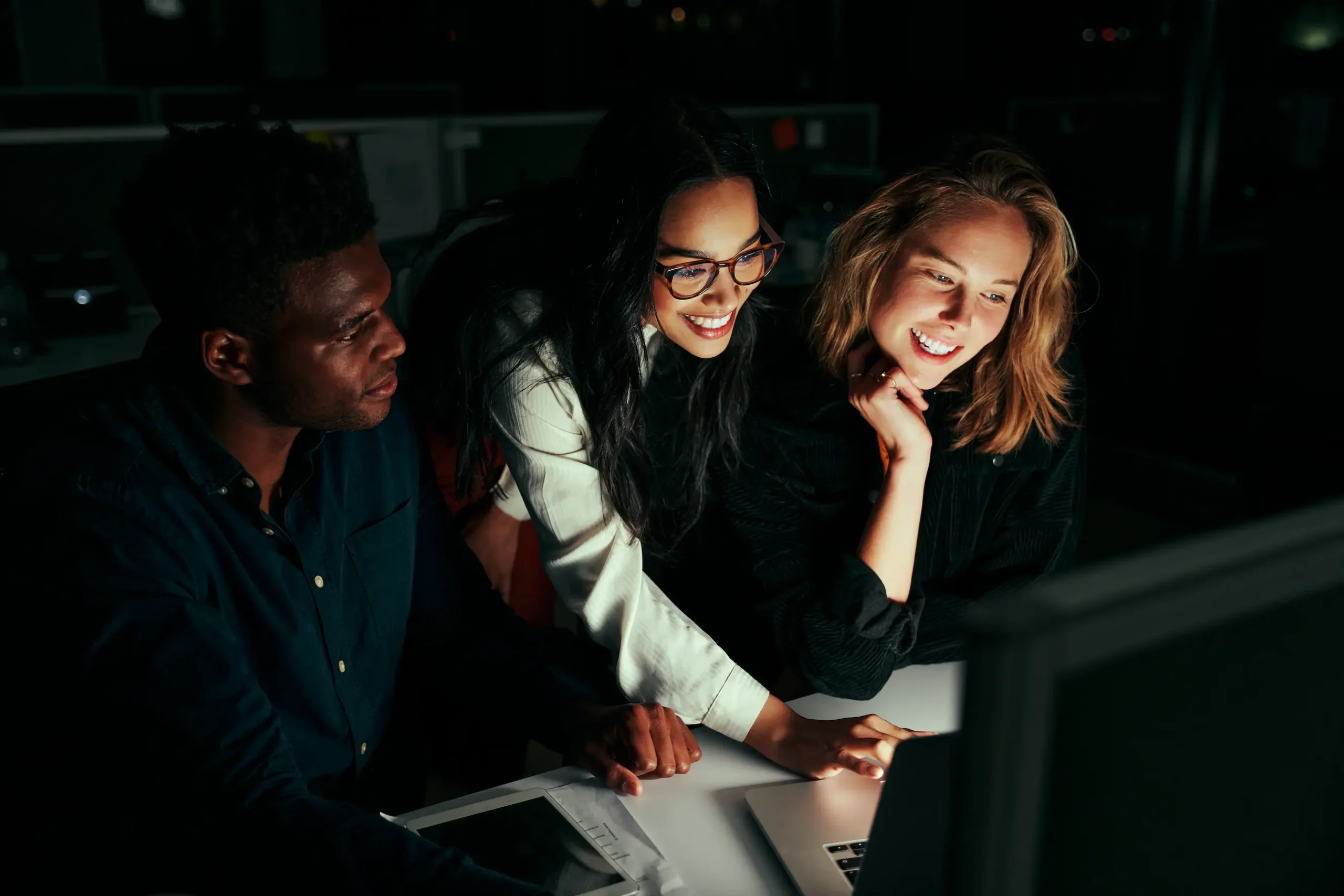 Group of happy diverse business people team working on project using laptop late in office at night